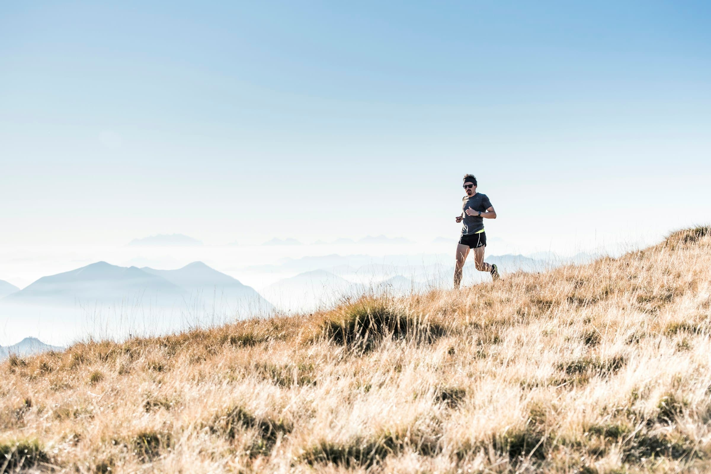 Trail runner crossing a high mountain meadow above the clouds